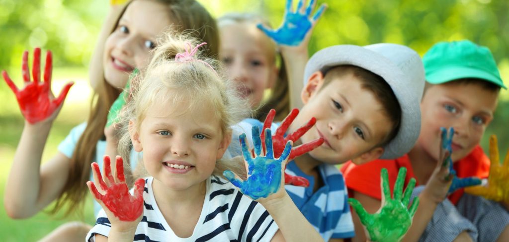 Dzieci mają ręce ubrudzone farbą i się uśmiechają